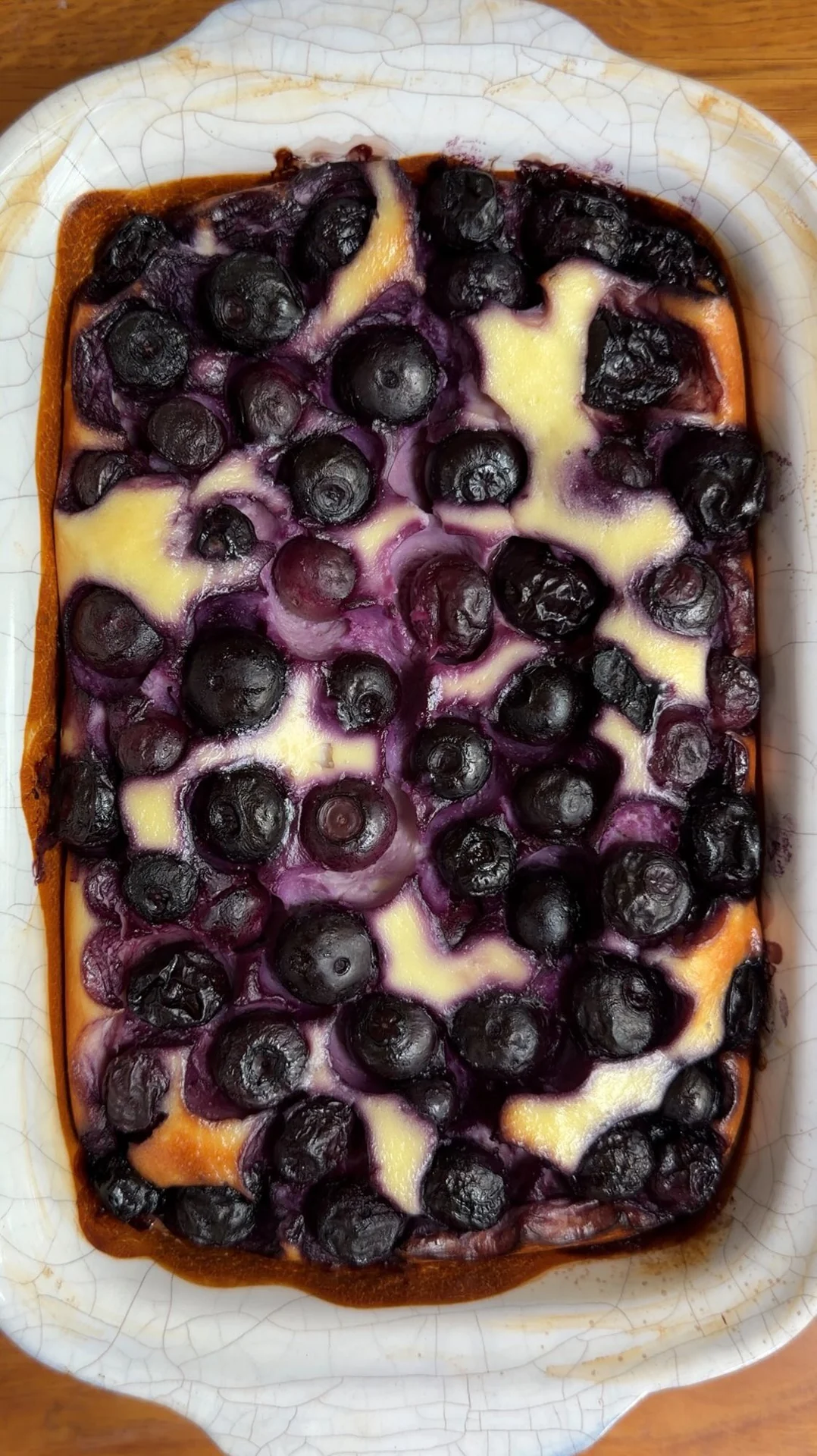 A blueberry yogurt bake in a white dish on a wooden table