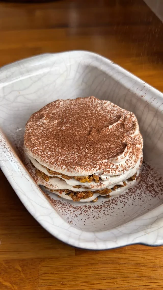 Coffee and yogurt dessert dusted with cocoa on a white scalloped plate
