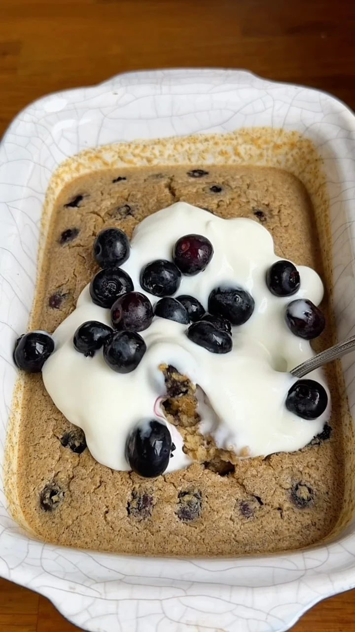 Golden baked oats with yogurt and blueberries in a white dish